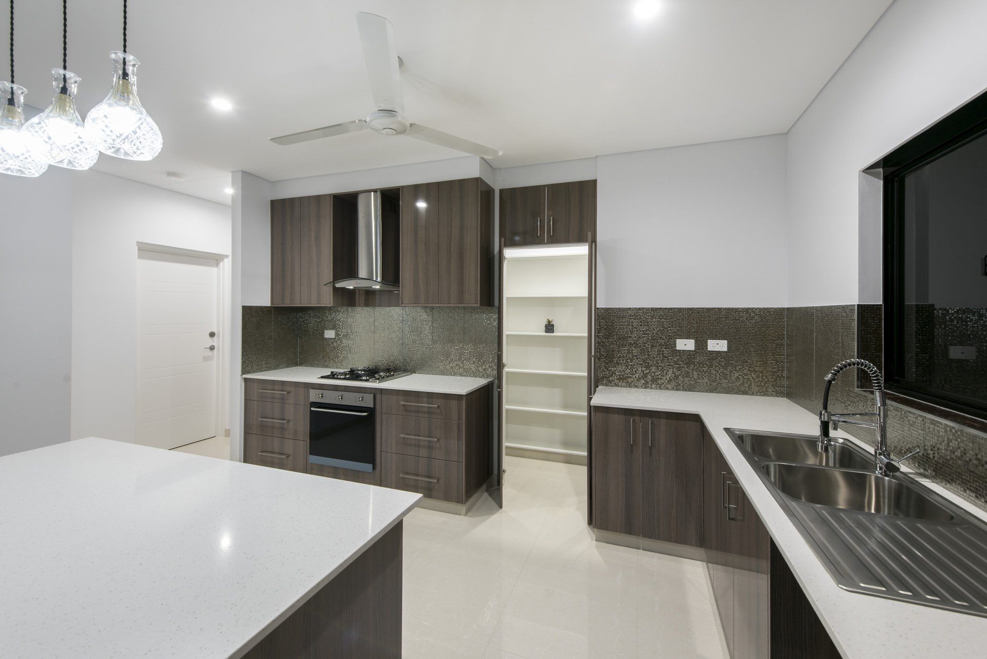 An empty kitchen with wooden cabinets and white counter tops