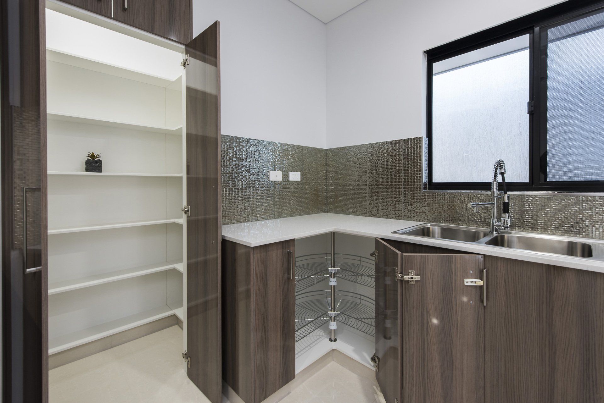 A kitchen with wooden cabinets , a sink , and a pantry.