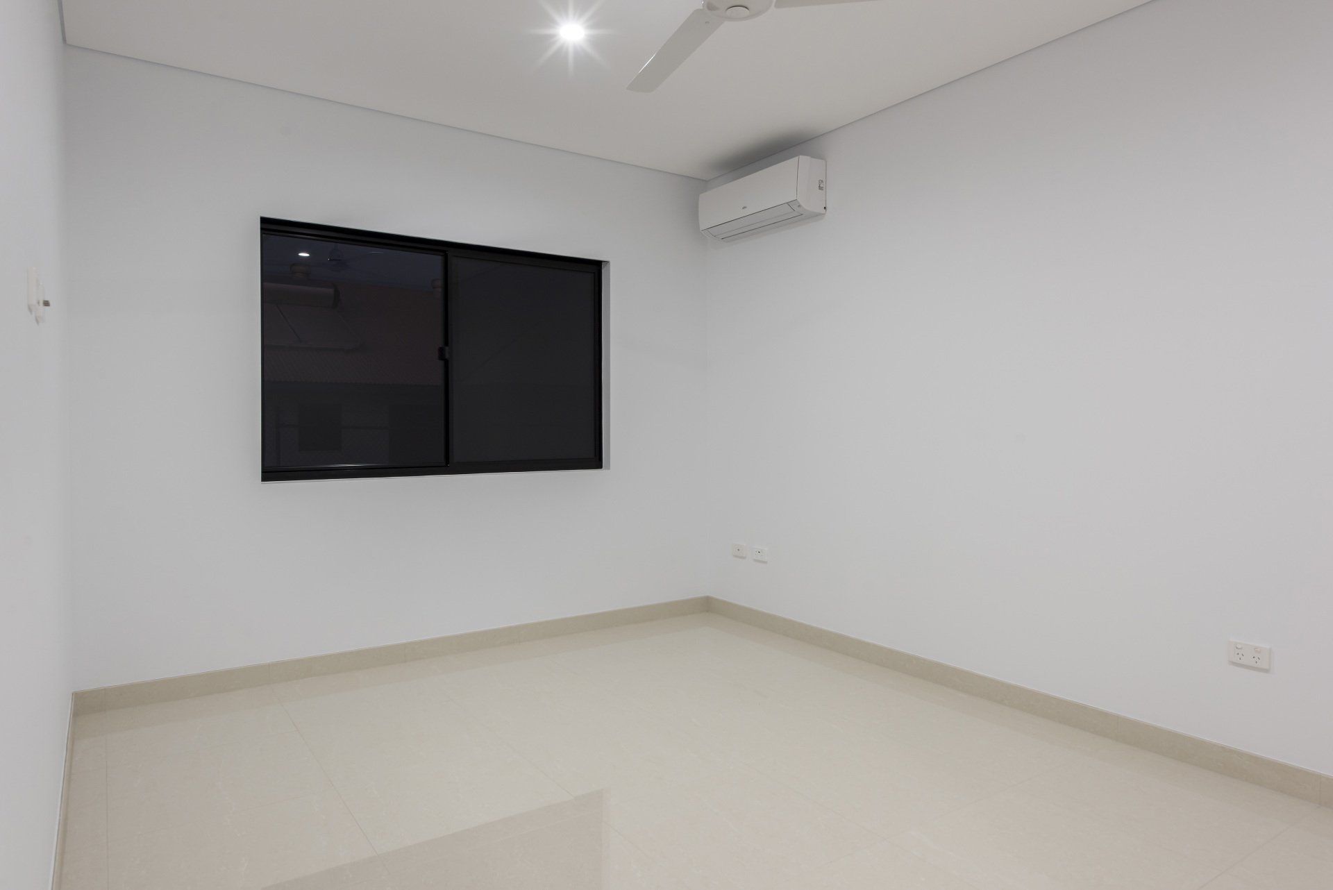 An empty room with a ceiling fan and a window.