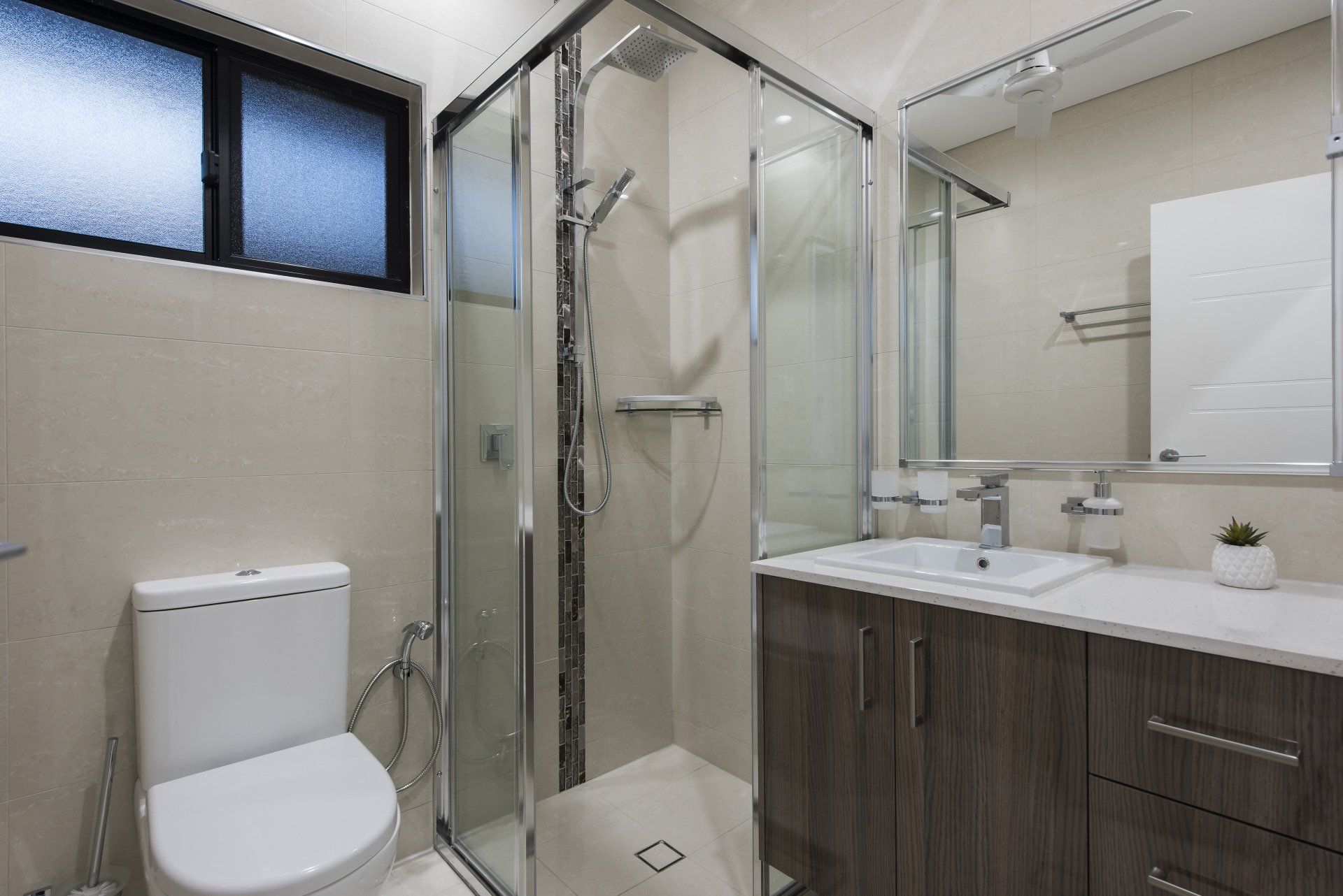 A bathroom with a toilet , sink and shower.