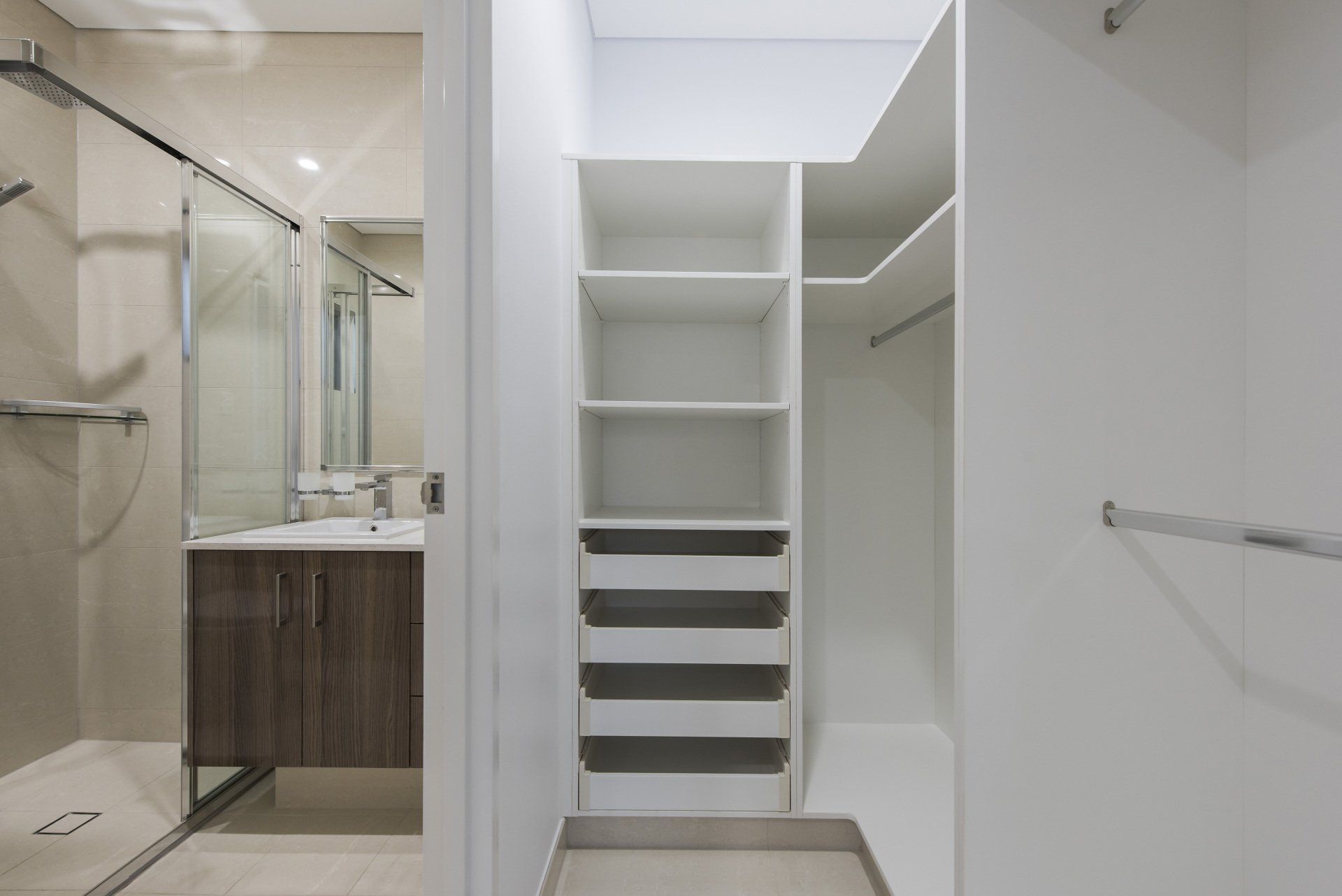 A bathroom with a walk in closet and a sink.