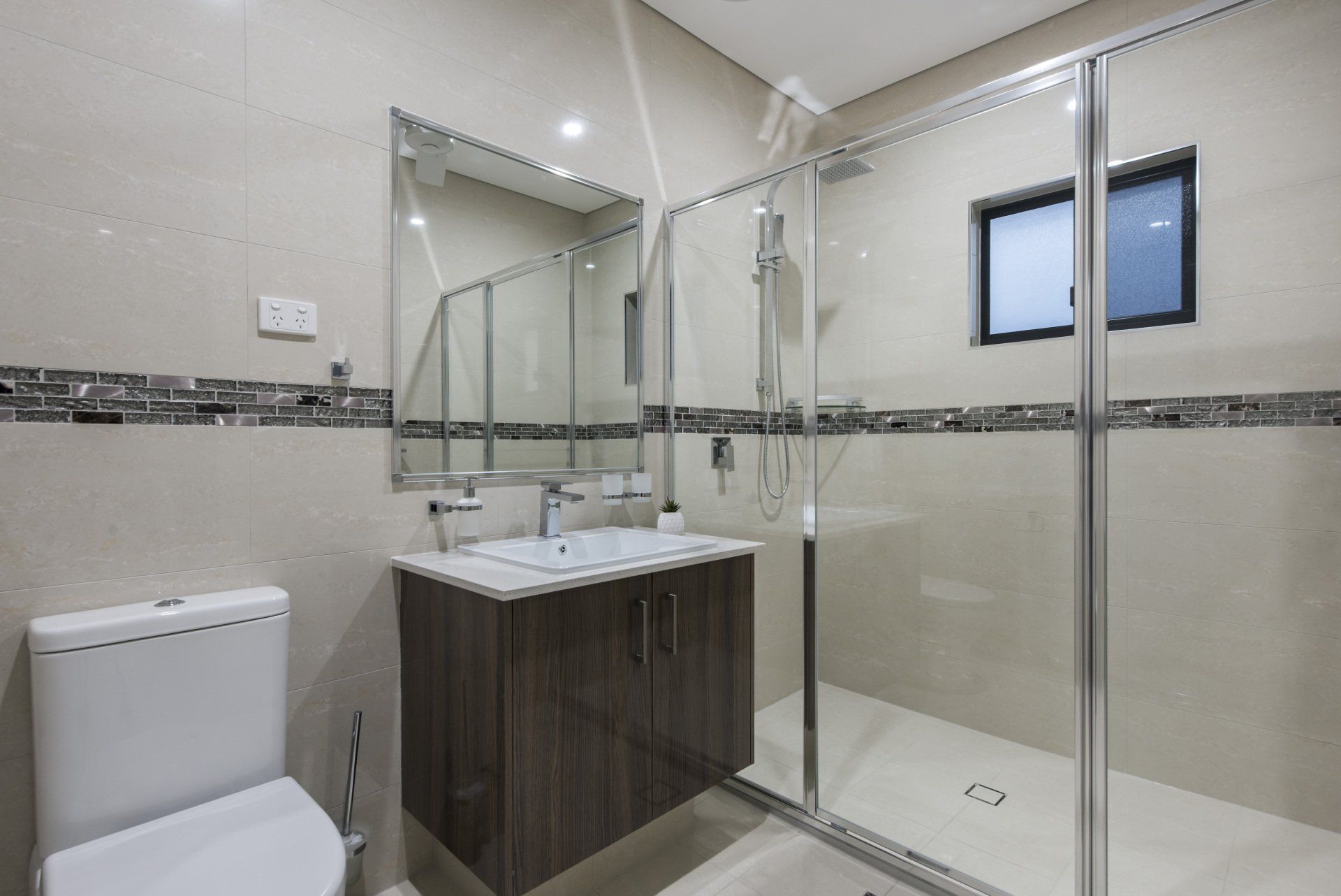 A bathroom with a toilet , sink , mirror and walk in shower.