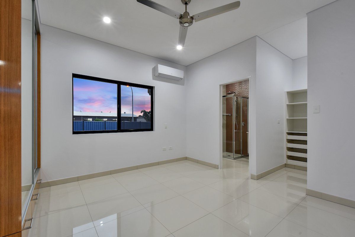 An empty room with a ceiling fan and two windows.