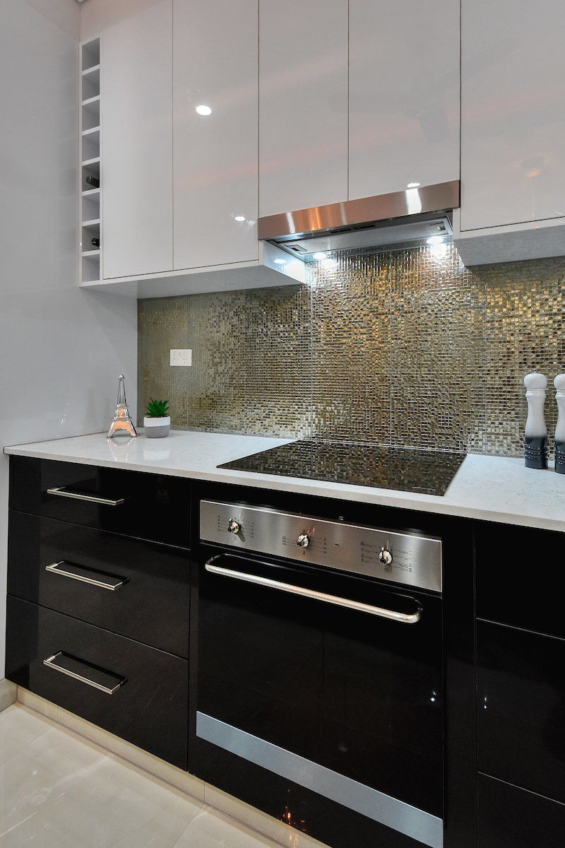 A kitchen with black cabinets and a stove top oven.