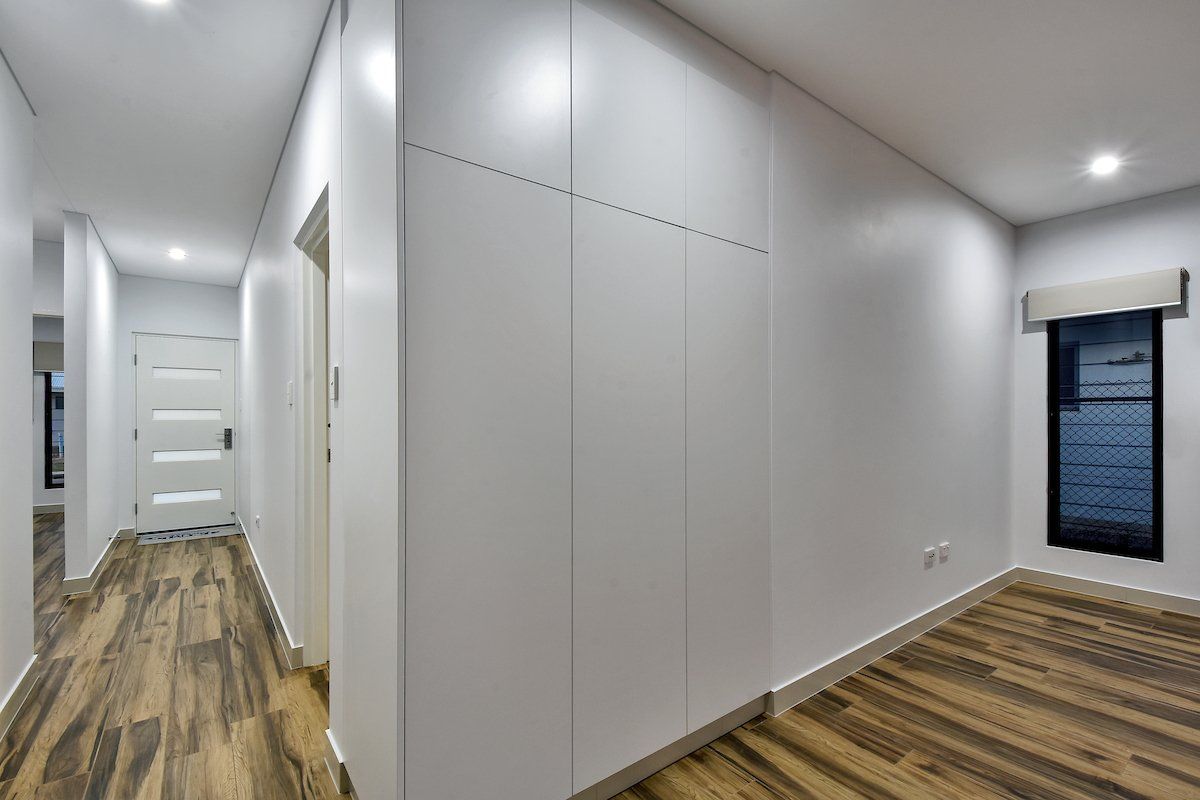 A hallway with white walls and wooden floors in a house.