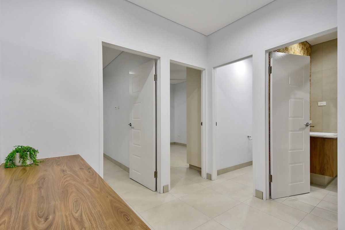 A hallway with three doors and a wooden table in the middle.