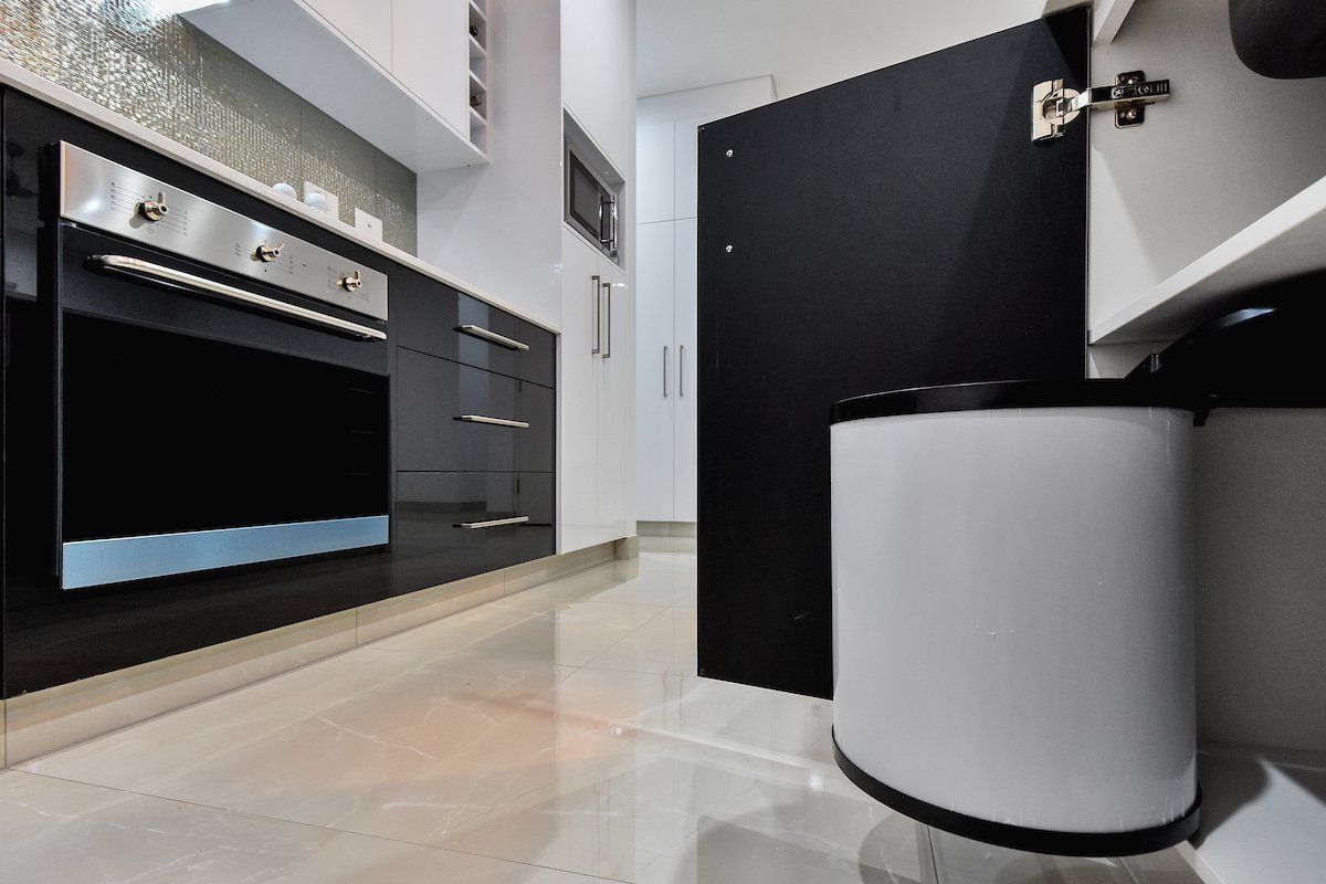 A kitchen with black and white cabinets and a stainless steel oven