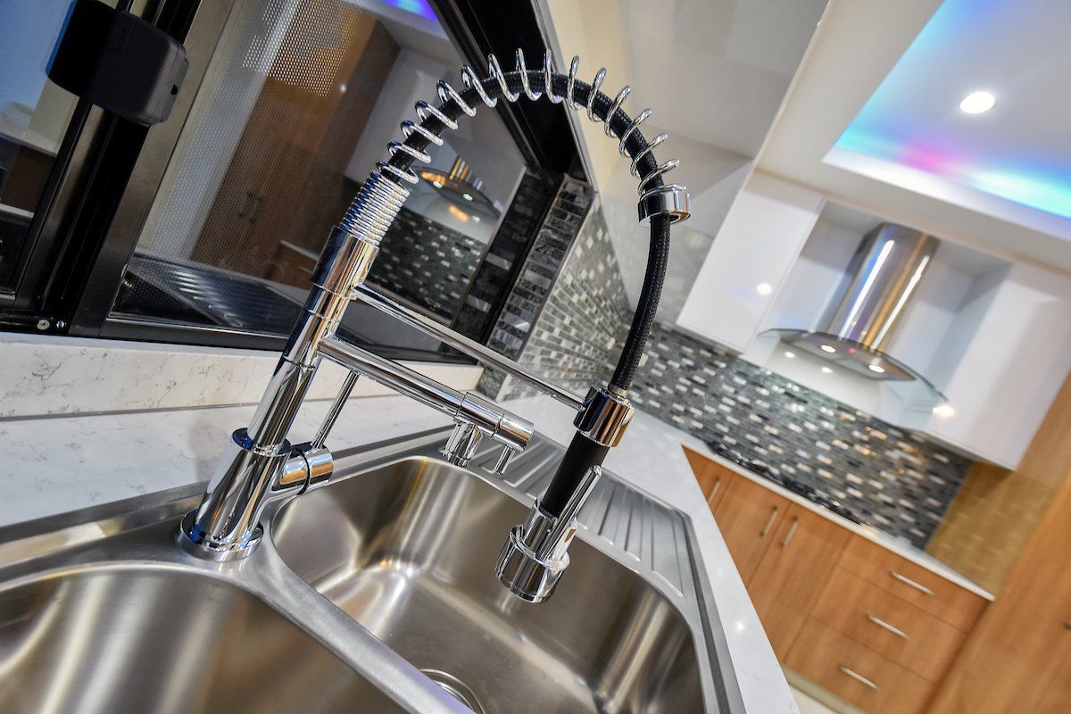 A kitchen sink with a stainless steel faucet