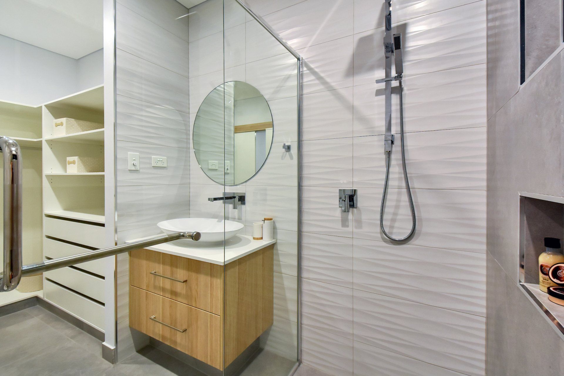 A bathroom with a sink , mirror , shower and walk in closet.