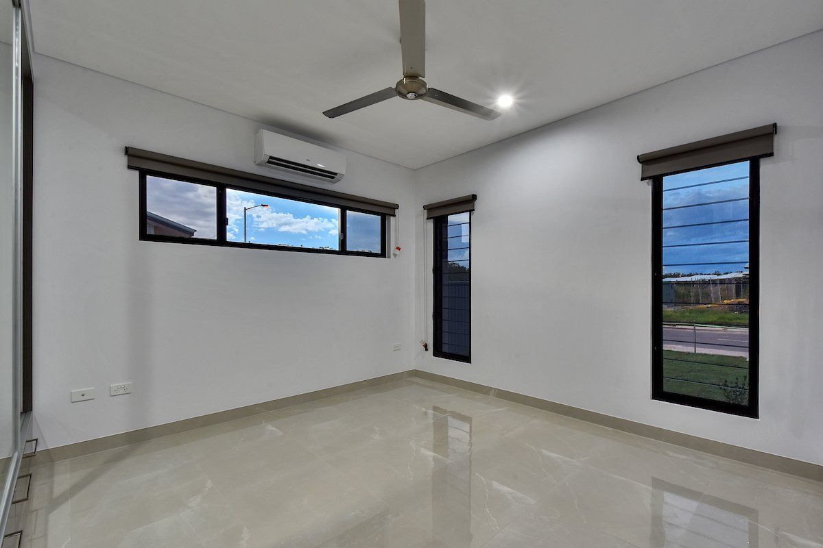 An empty room with a ceiling fan and two windows
