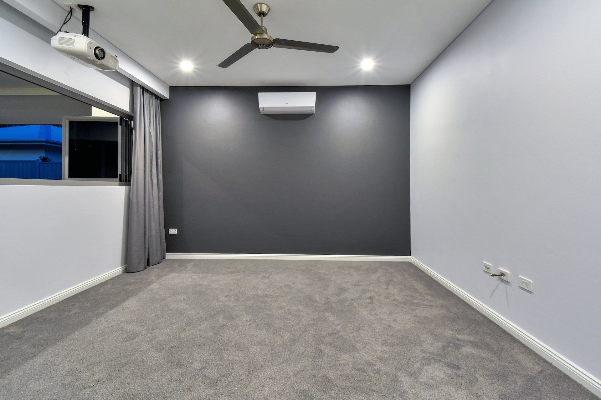 An empty room with a ceiling fan and a projector