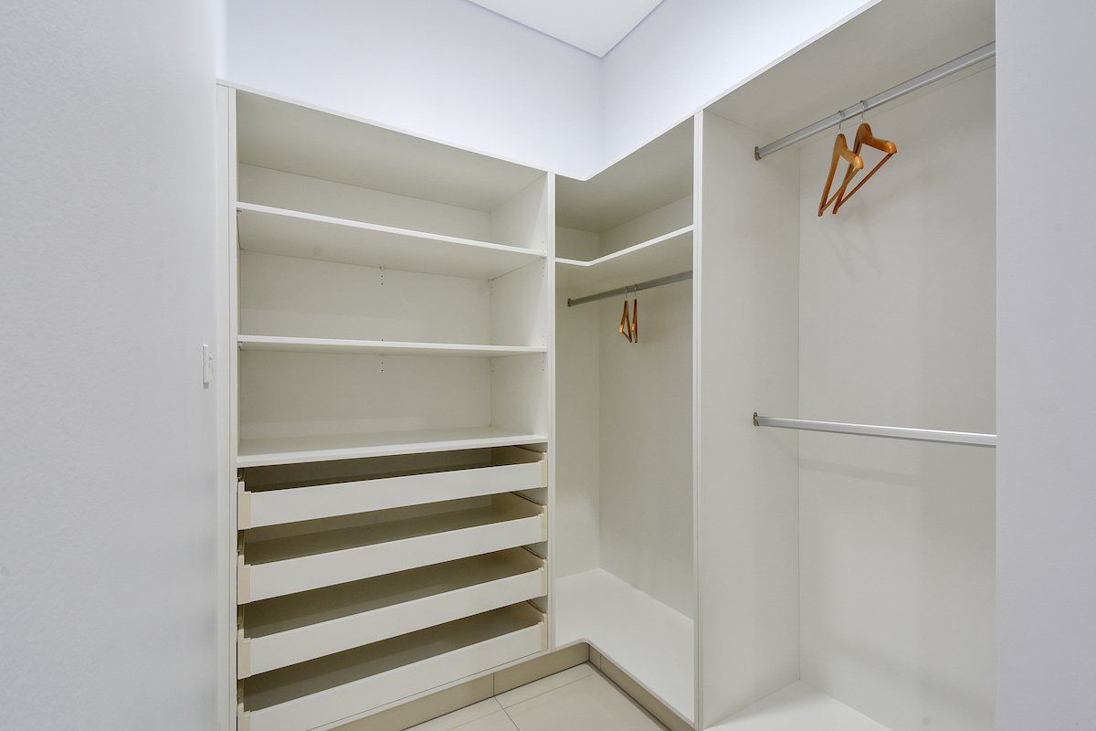 A walk in closet with a lot of shelves and clothes hangers.