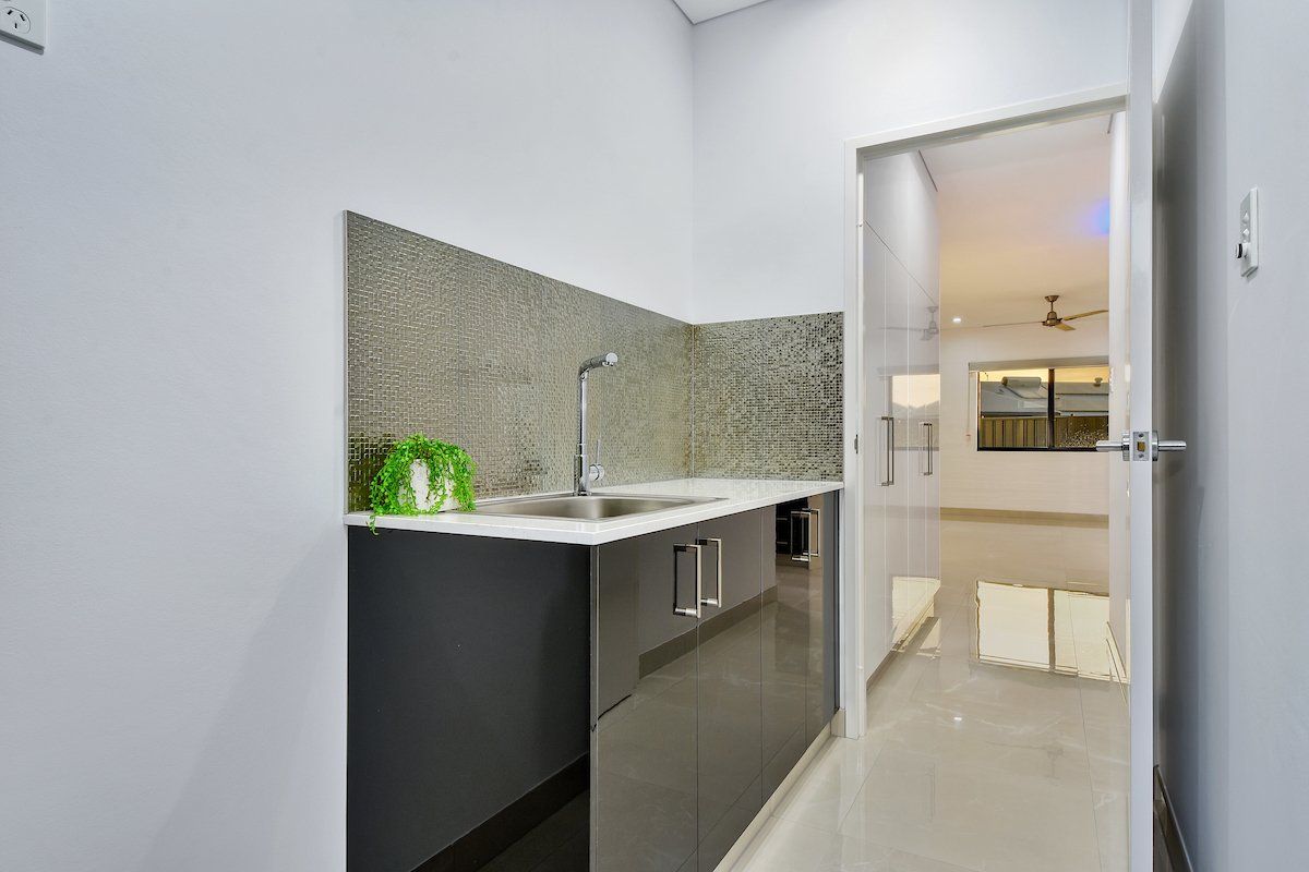 A kitchen with a sink , cabinets and a door leading to a living room.