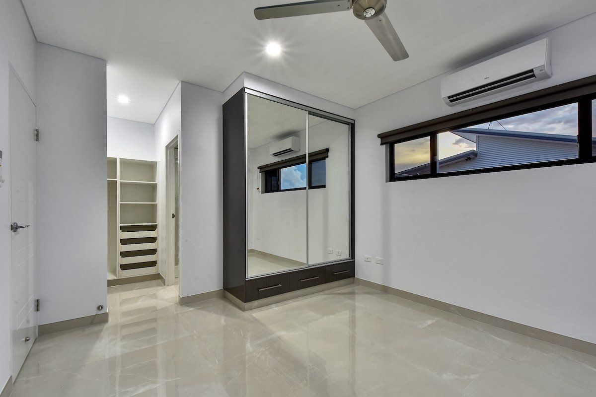 An empty bedroom with a ceiling fan and a large mirrored wardrobe.