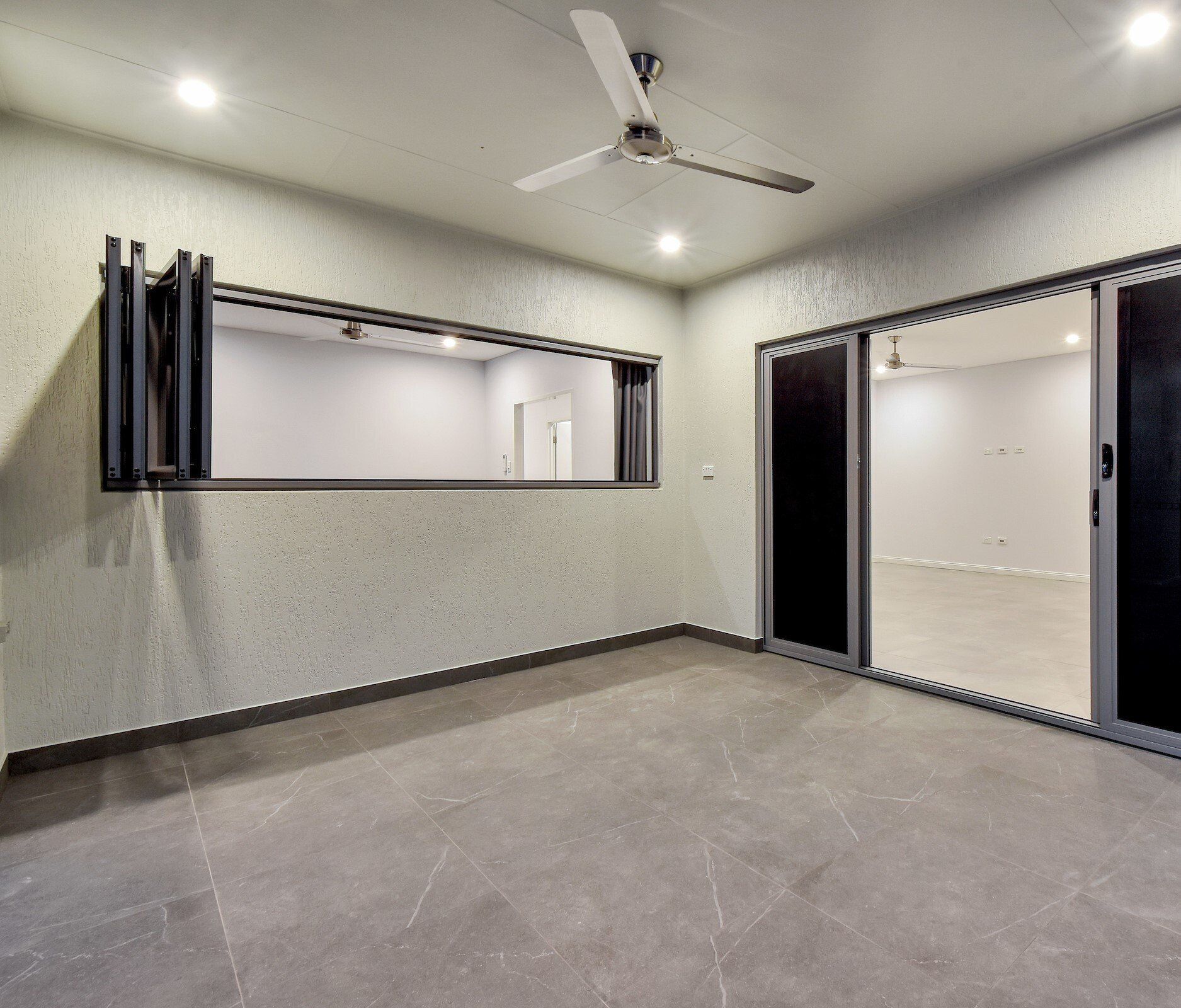 An empty room with a ceiling fan and sliding glass doors