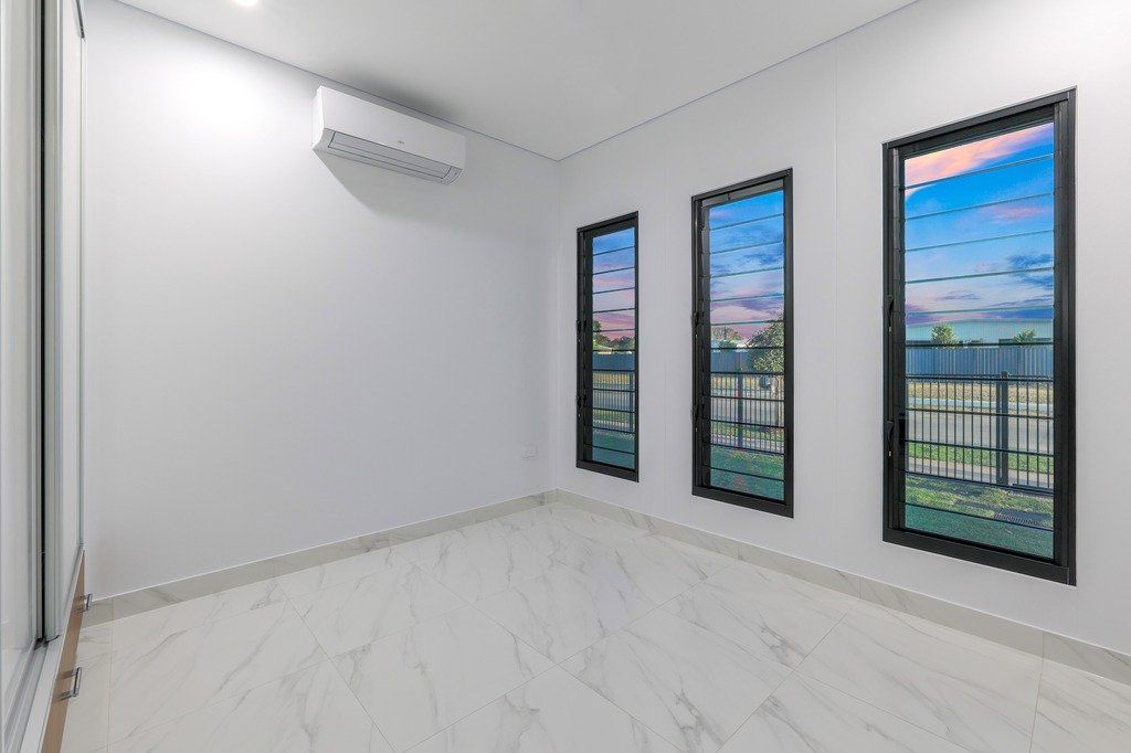An empty room with three windows and a ceiling fan.