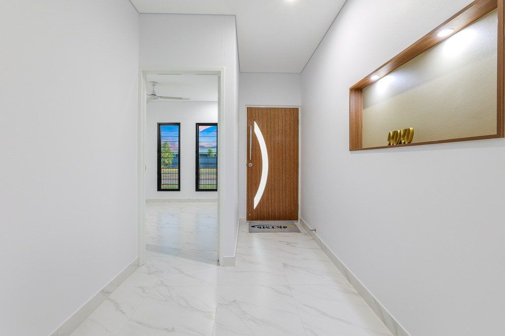 A hallway with a wooden door and a mirror on the wall