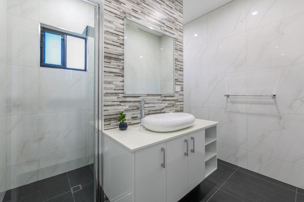 A bathroom with a sink , mirror , and shower.