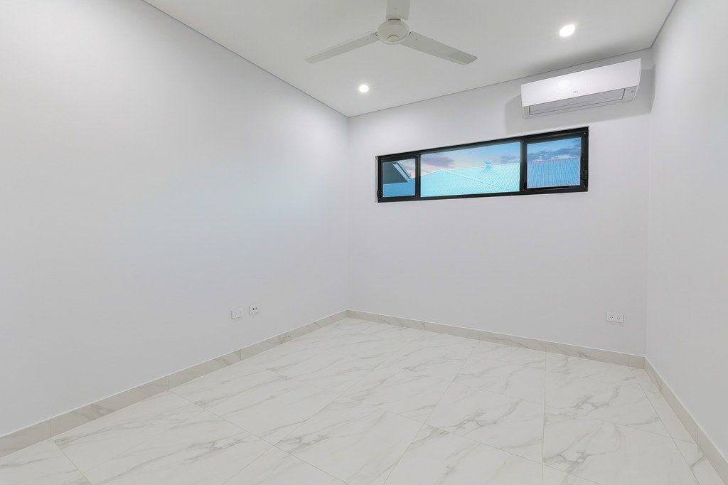 An empty room with a ceiling fan and three windows.