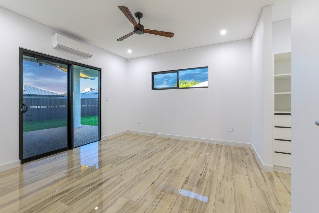 An empty room with a ceiling fan and sliding glass doors