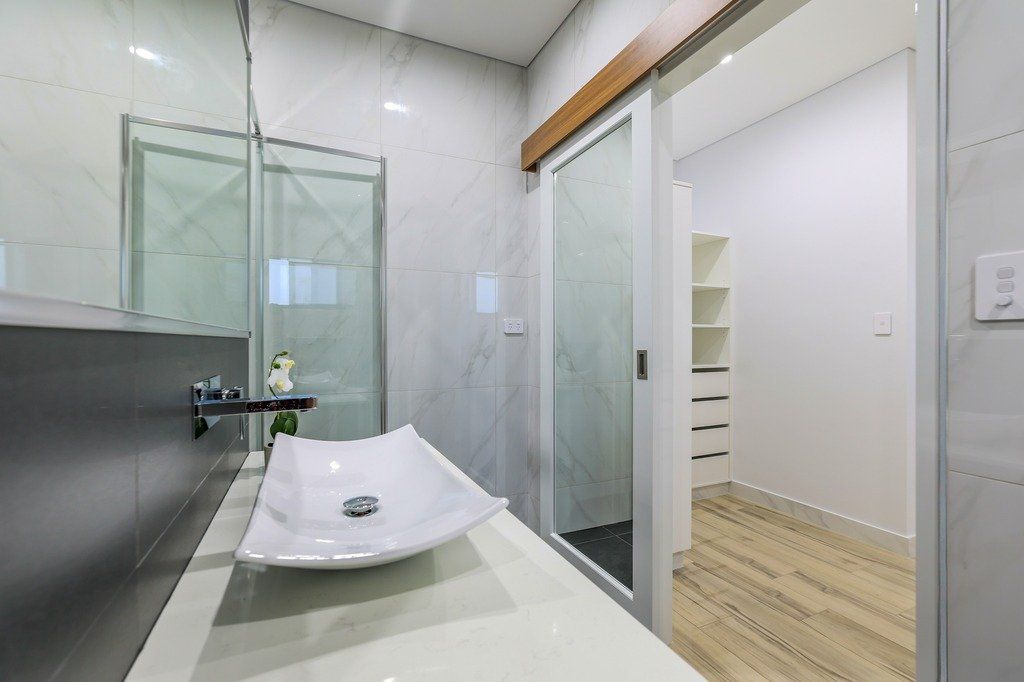 A bathroom with a sink , mirror and sliding glass door.
