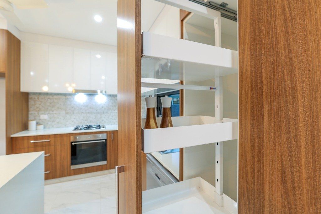 A kitchen with wooden cabinets and a sliding pantry