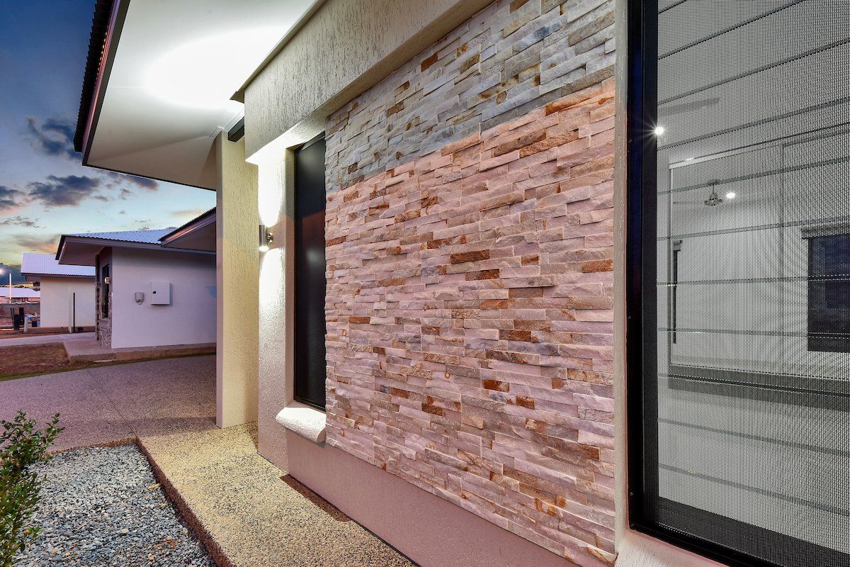 The side of a house with a brick wall and a window.