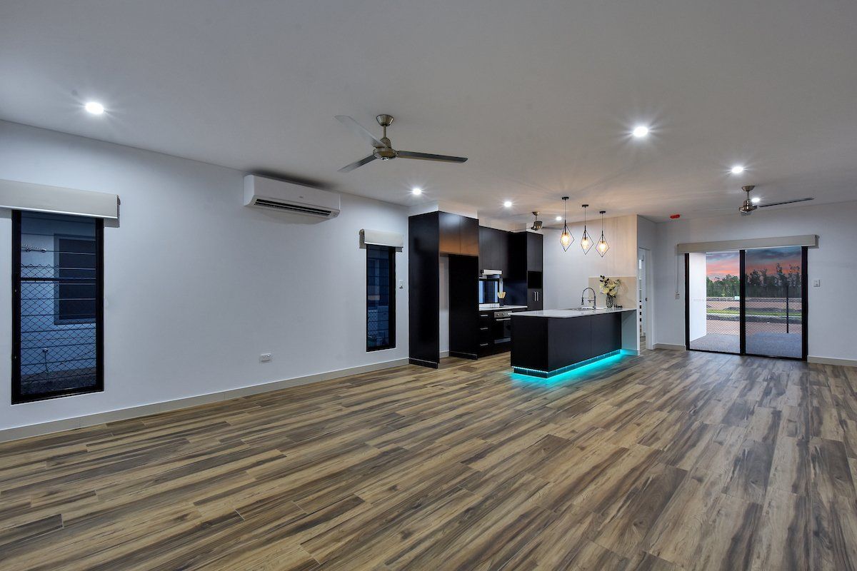 A large empty room with a wooden floor and a ceiling fan.