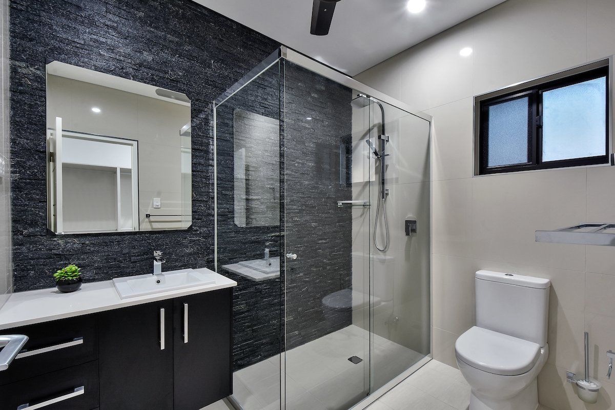 A bathroom with a toilet , sink , mirror and walk in shower.