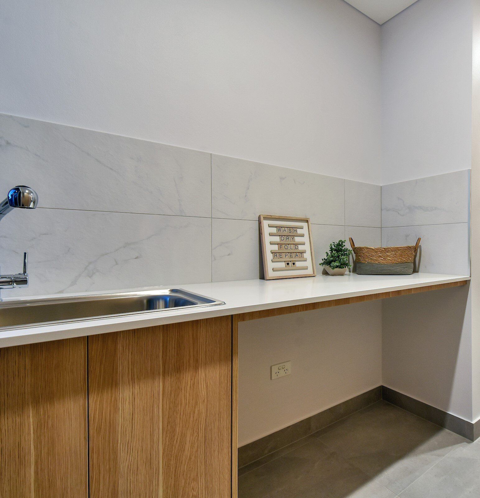 A kitchen with wooden cabinets , a sink , and a clock on the counter.