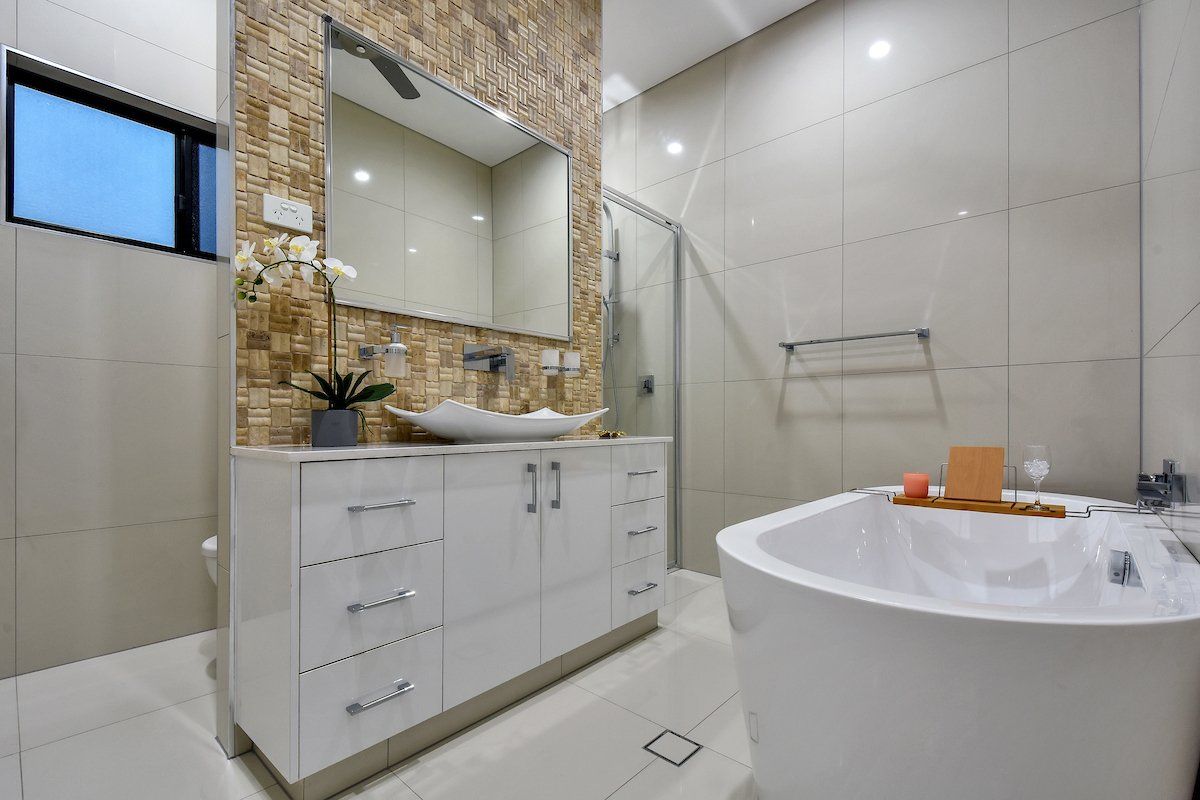 A bathroom with a bathtub , sink and mirror.