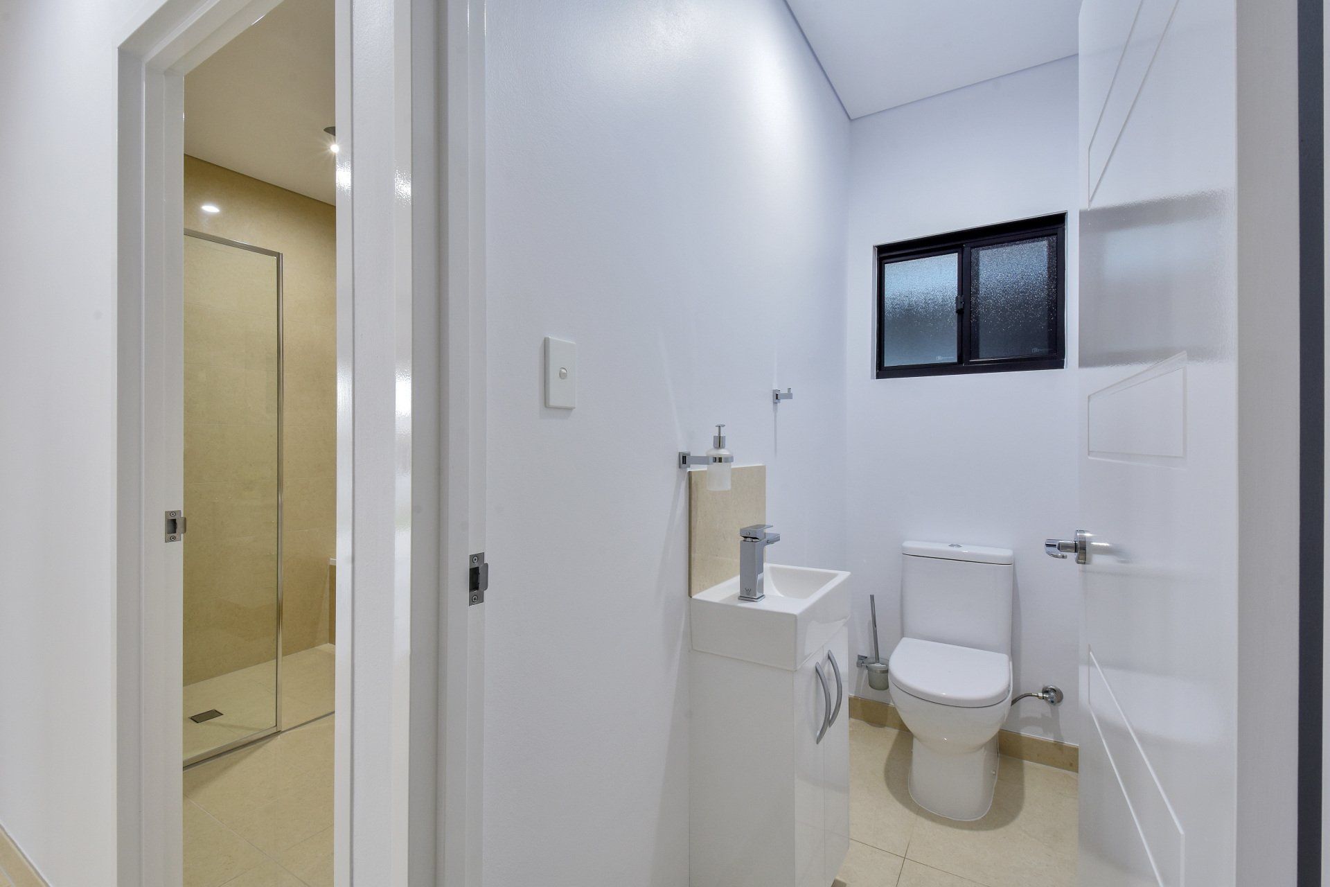 A bathroom with a toilet , sink and shower.