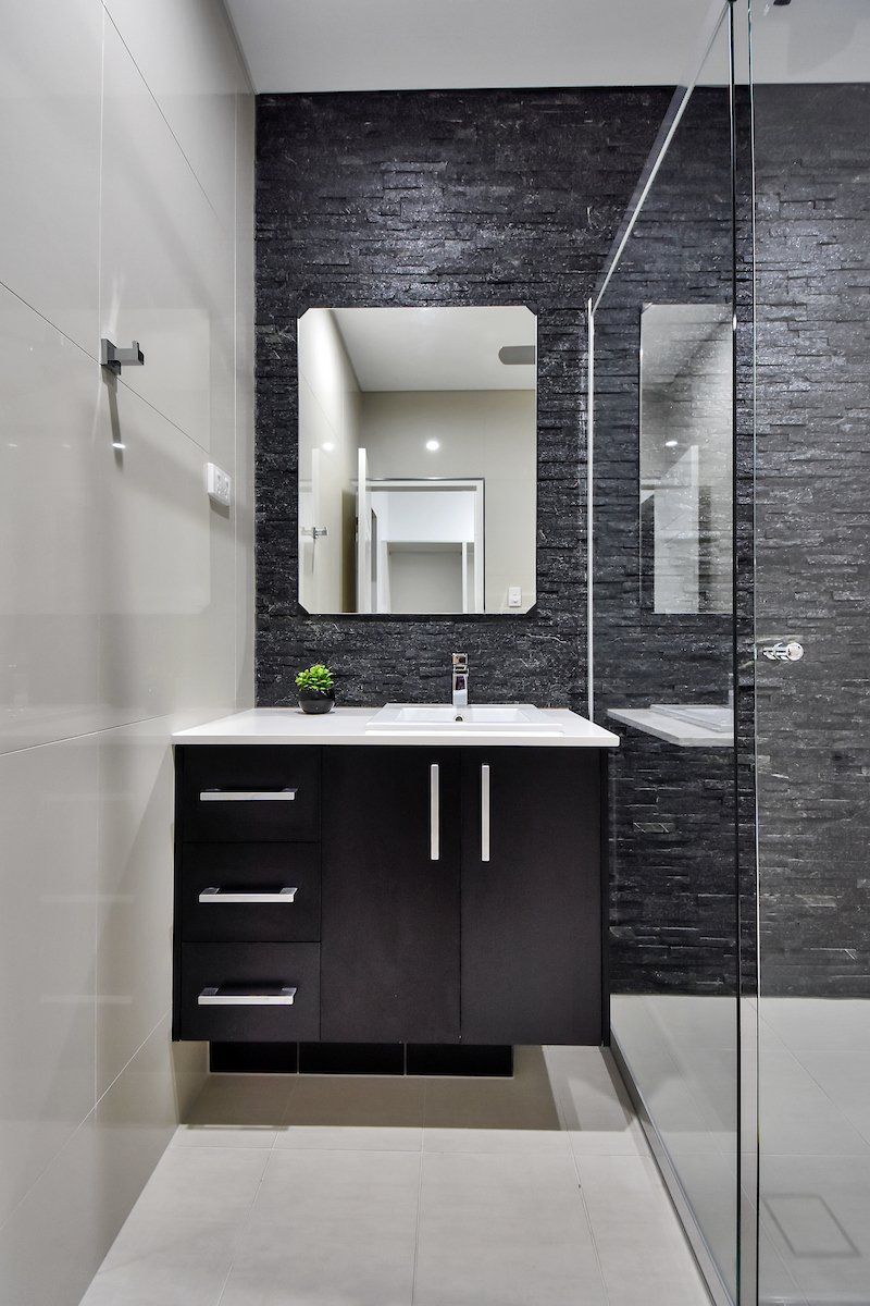 A bathroom with a sink , mirror and walk in shower