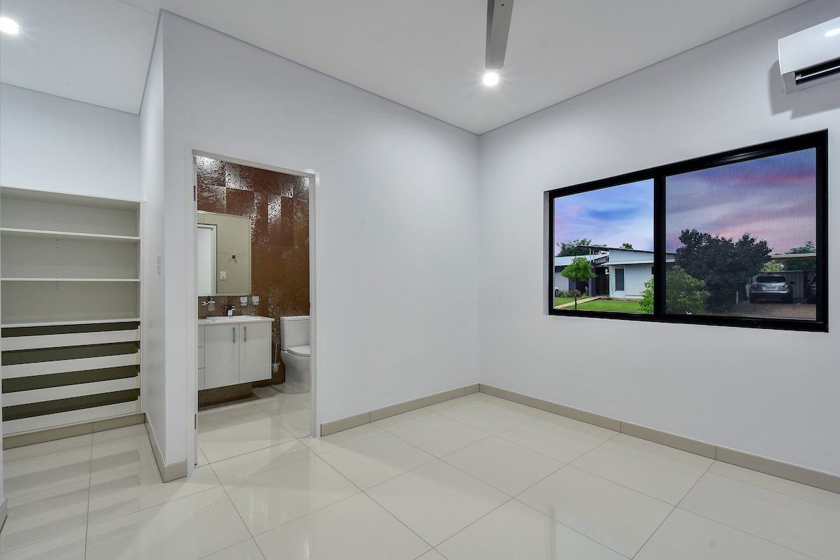 An empty room with a bathroom and two windows.