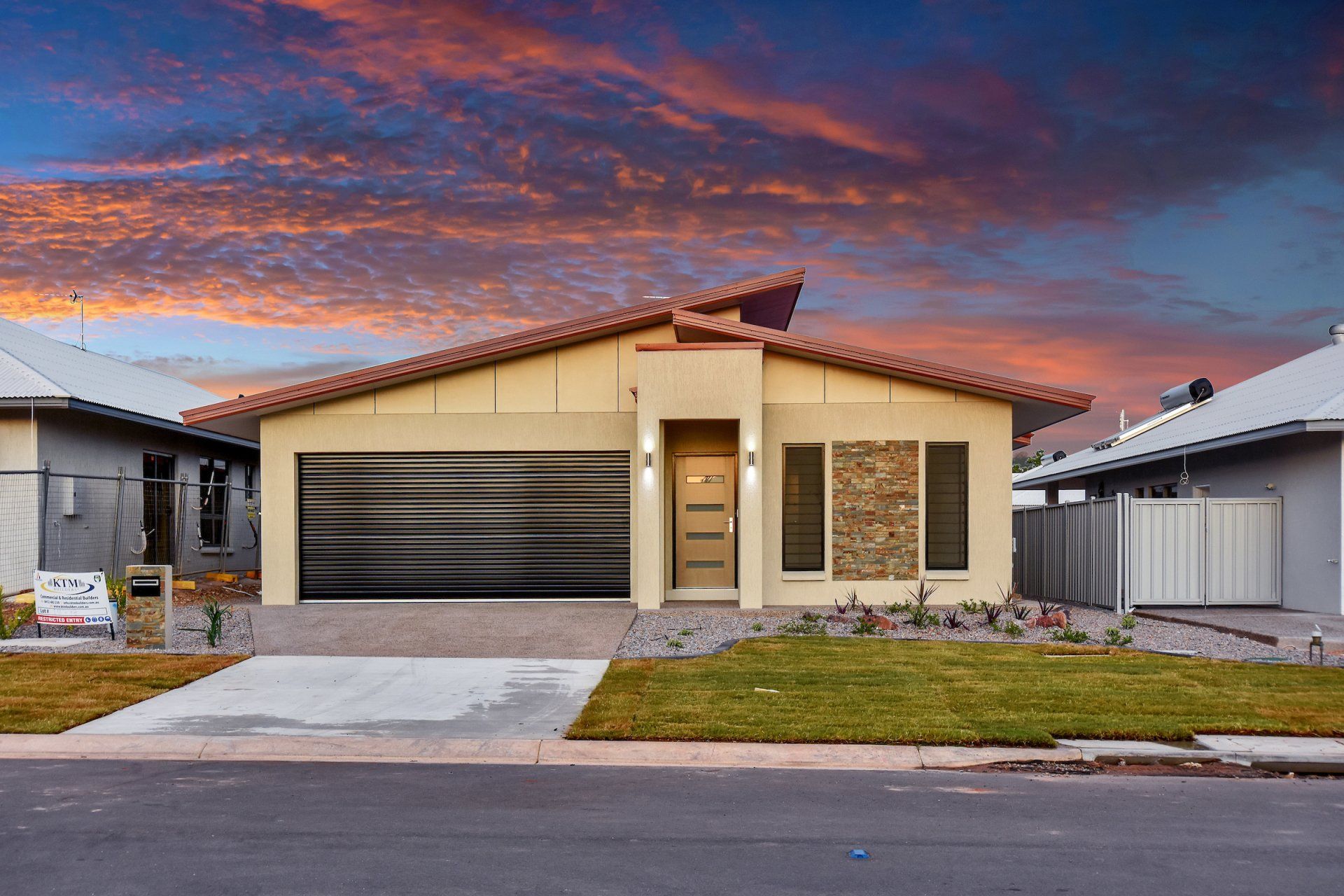 A house with a large garage and a sunset in the background.