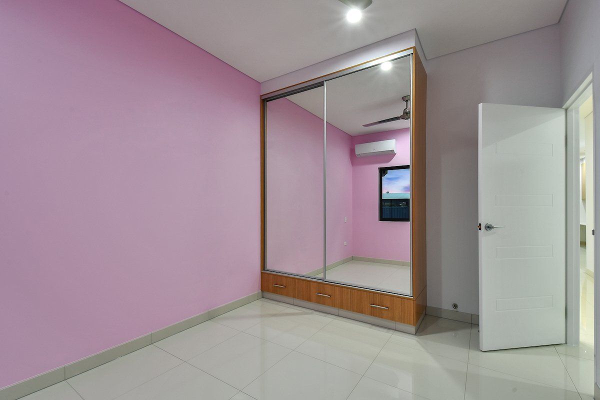 A bedroom with pink walls and a large mirrored wardrobe.