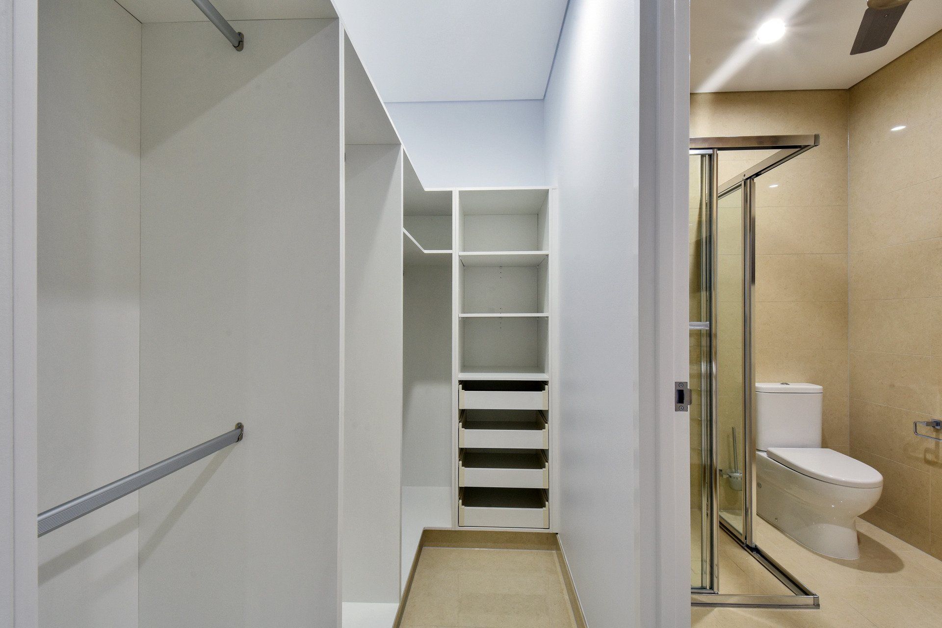 A walk in closet next to a bathroom with a toilet