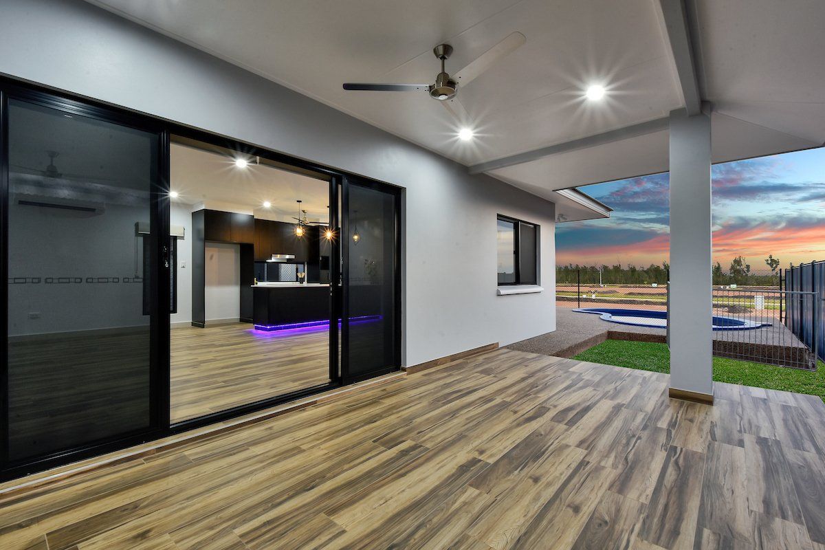 A large patio with sliding glass doors leading to a kitchen and a pool.