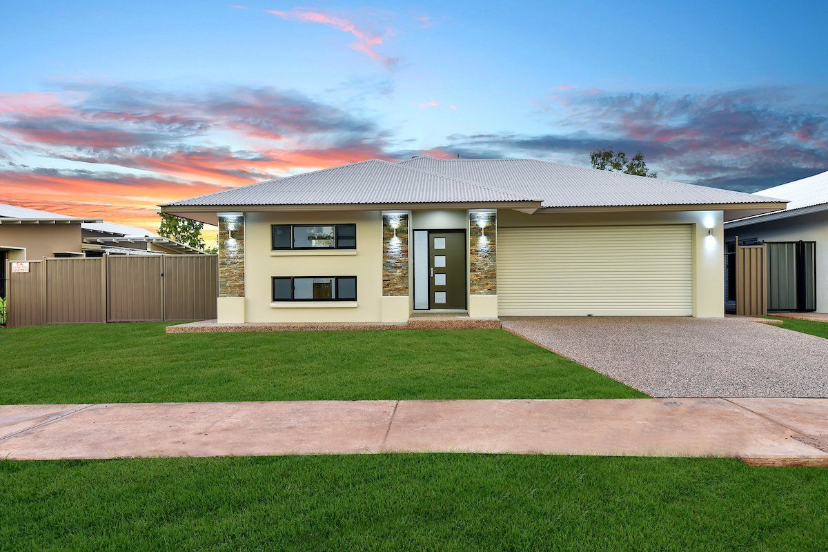 A white house with a large driveway and a fence in front of it.