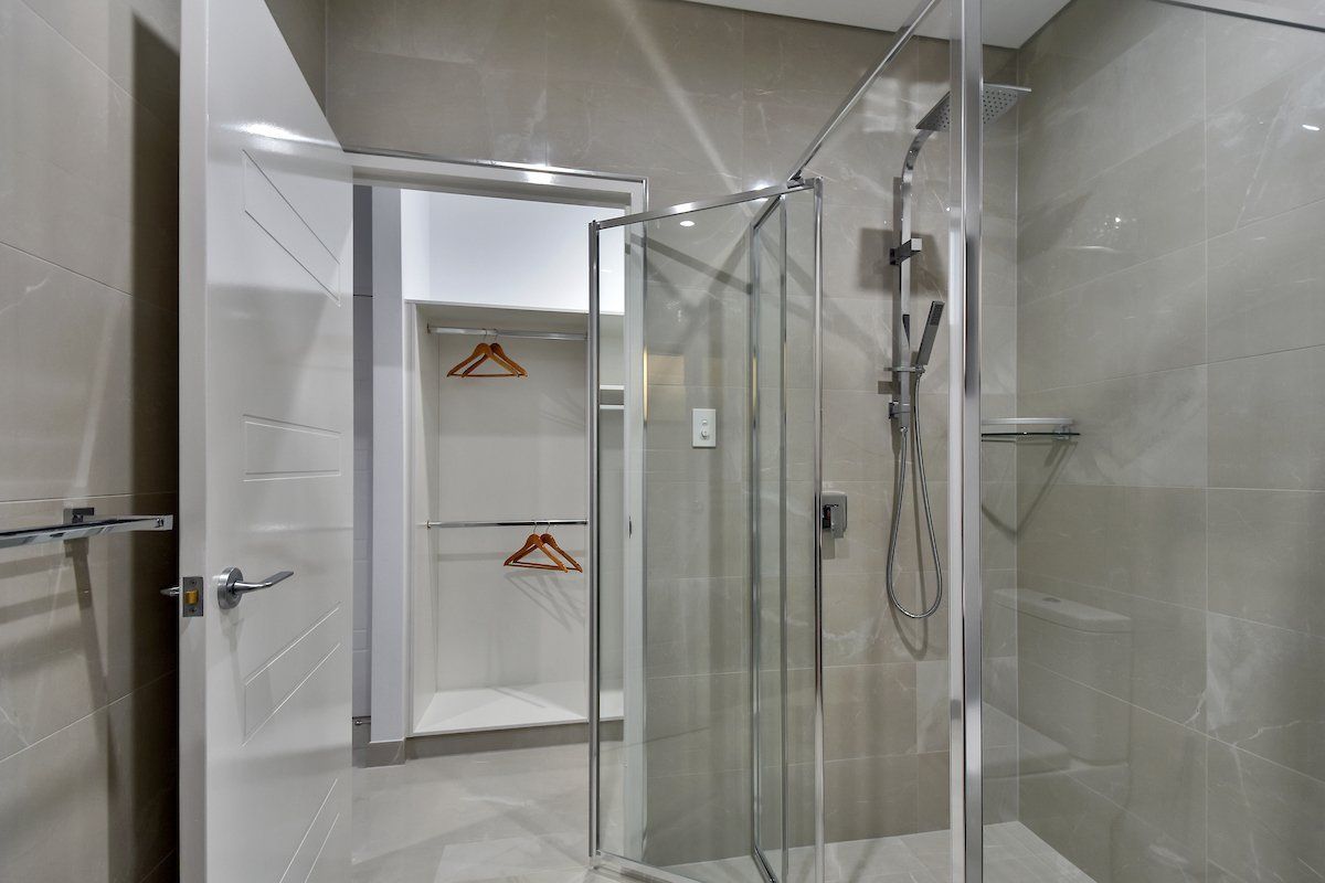 A bathroom with a walk in shower and a glass door.