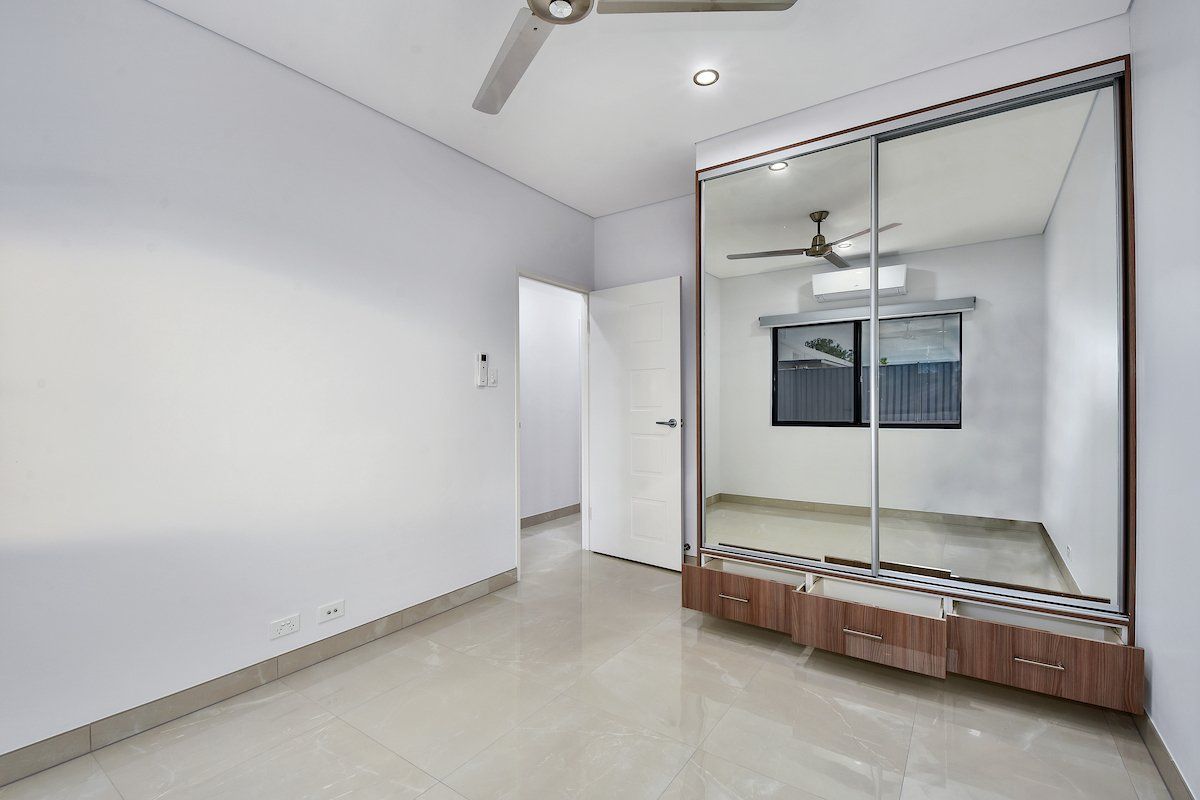 An empty bedroom with a large mirrored wardrobe and a ceiling fan.
