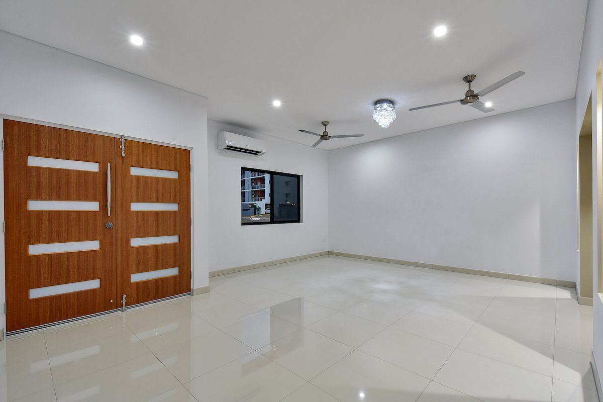 A large empty room with a ceiling fan and a window.