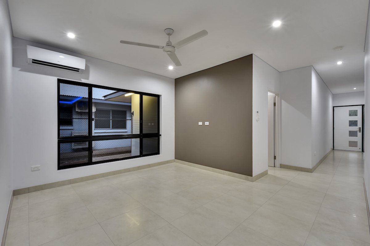 An empty room with a ceiling fan and two windows