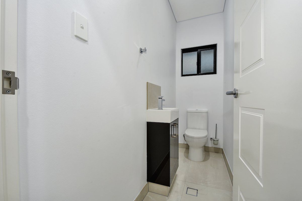 A bathroom with a toilet , sink and window.