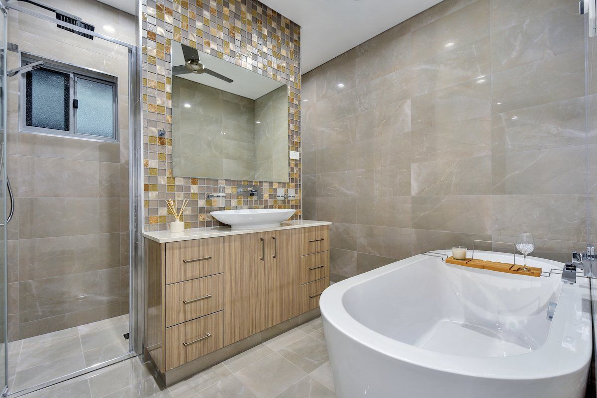 A bathroom with a tub , sink , mirror and shower.