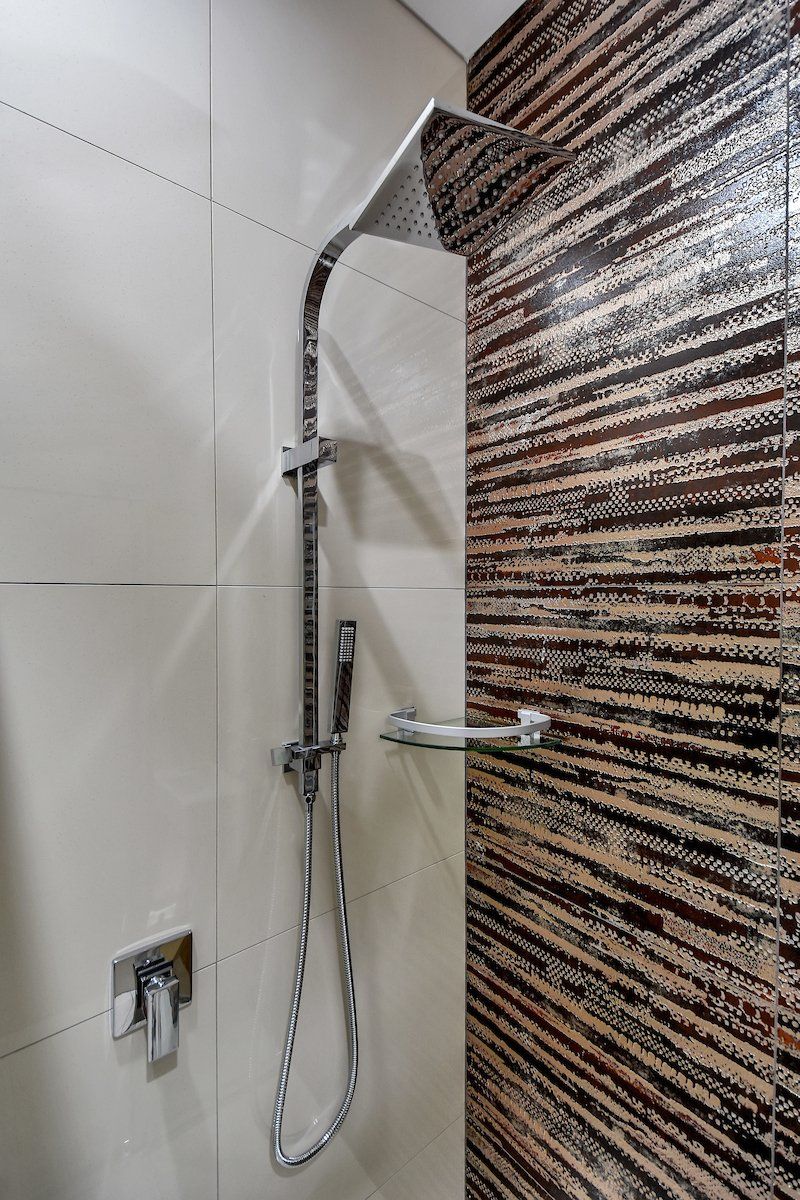 A bathroom with a shower head and a shelf.