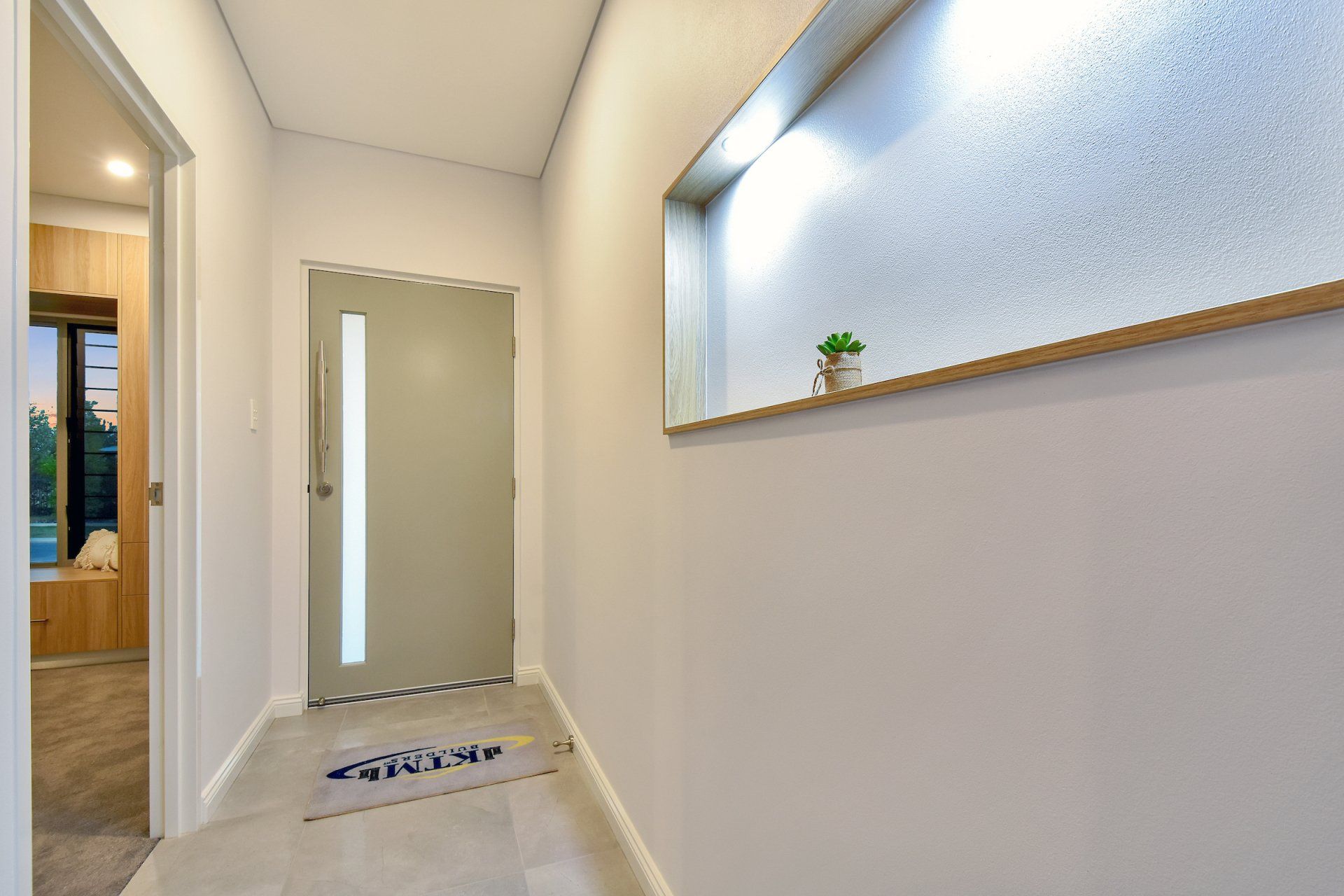 A hallway with a door and a plant on the wall.