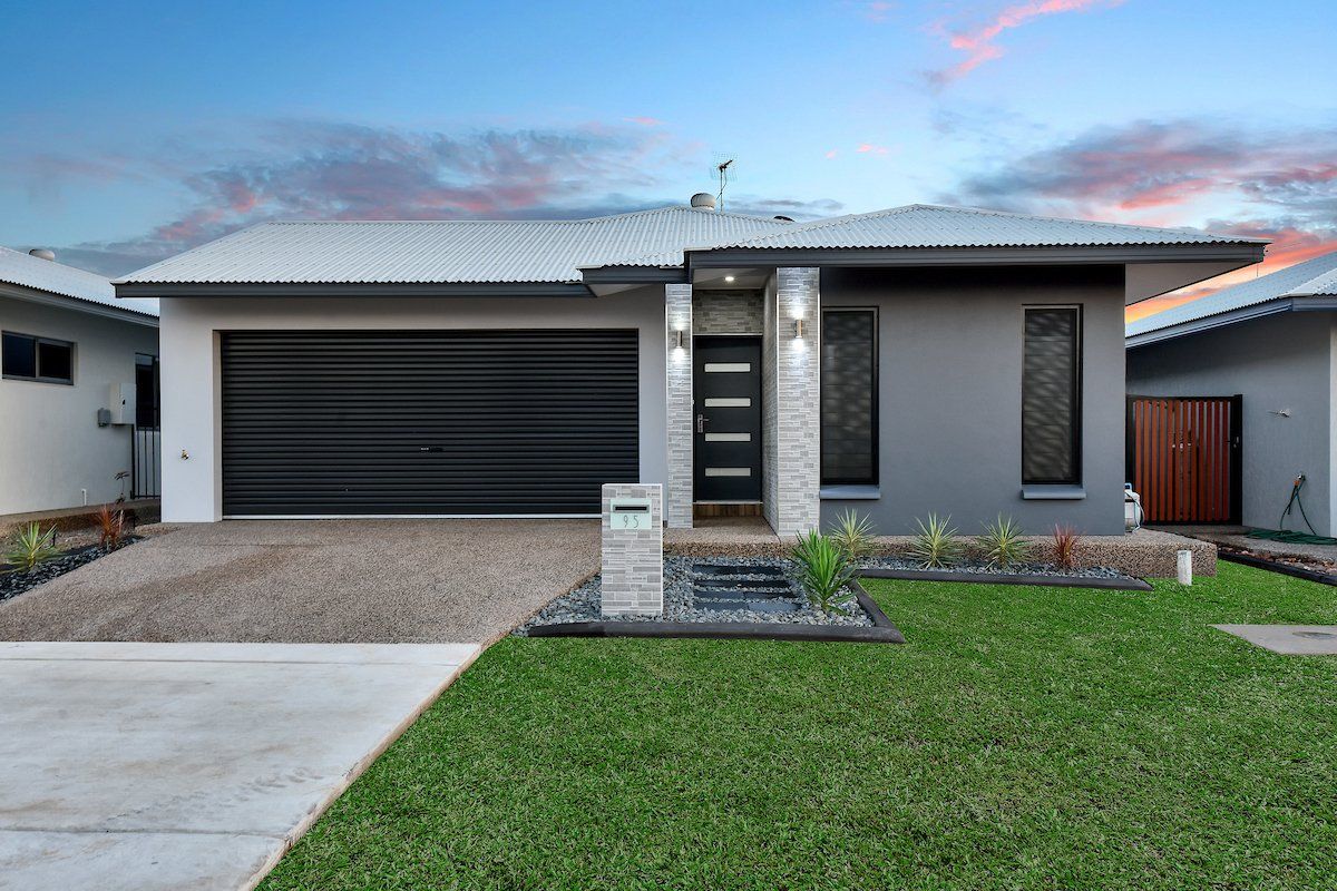 A modern house with a large garage and a lush green lawn in front of it.