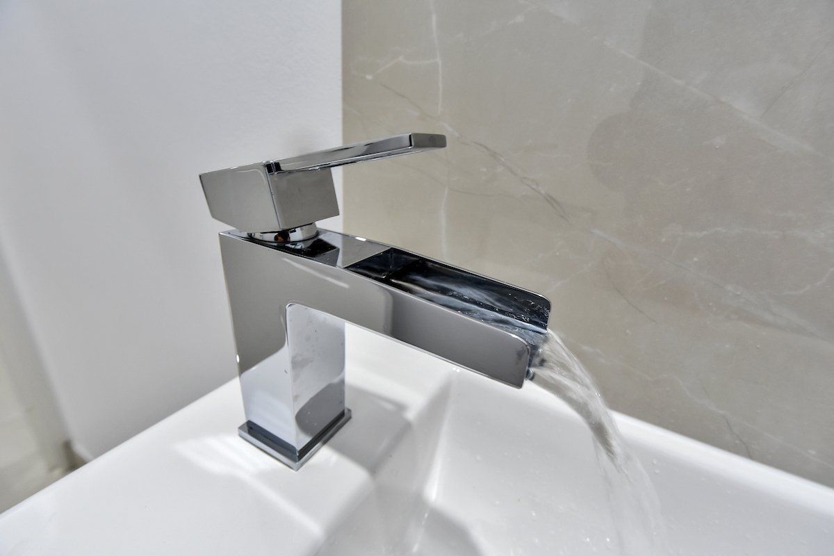 A bathroom sink with a chrome faucet and water running out of it.