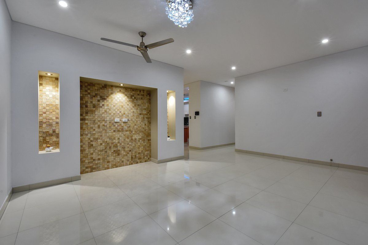 An empty living room with a ceiling fan and a stone wall.